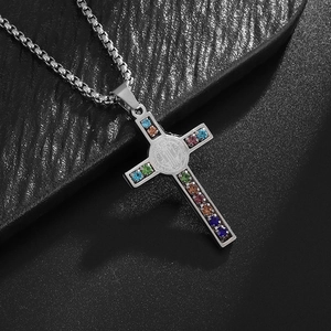 Macro shot of silver cross pendant with rainbow zircons and St. Benedict medal on box chain