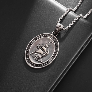Close-up of vintage pirate ship relief on oval silver pendant with box chain