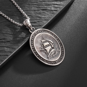 Macro detail of retro sailboat relief pendant on vintage steel box chain necklace