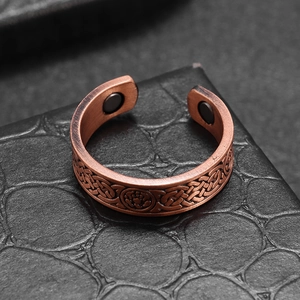 Macro shot of copper magnetic therapy ring with Celtic knot patterns on leather