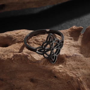 Macro detail of black stainless steel witch's knot ring on rustic wood background