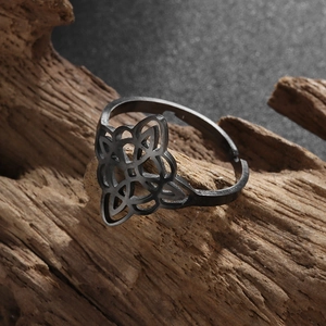 Macro detail of black stainless steel Celtic witch knot ring on rustic wooden base