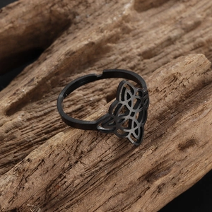Macro shot of black stainless steel Celtic knot ring on natural wood surface