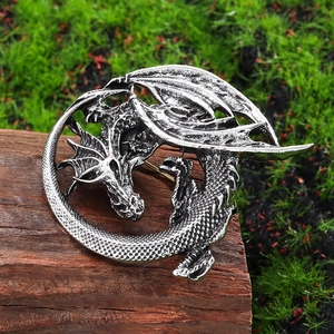 Vintage silver dragon brooch with detailed scales on wood block background