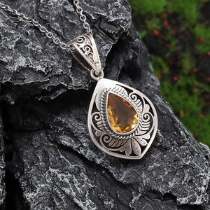 Macro detail of teardrop yellow stone pendant with vintage floral silver carving