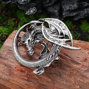 Vintage silver dragon brooch with detailed scales and wings on a rustic wooden background