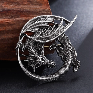 Macro shot of vintage silver dragon brooch with detailed scales on textured wood