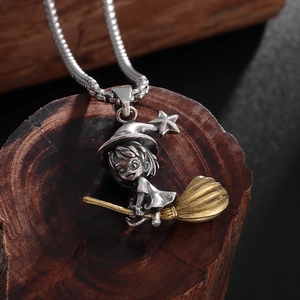 Close-up of retro silver and gold flying witch pendant on a vintage metal box chain