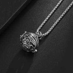 Close-up of vintage hollow sphere pendant with intricate filigree and box chain detail