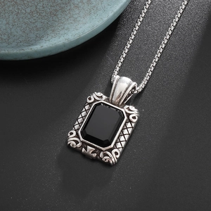 Detailed close-up of square black gemstone pendant with vintage engraved silver pattern