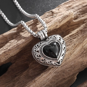 Détail du collier médaillon coeur vintage avec pierre noire sur fond de bois rustique