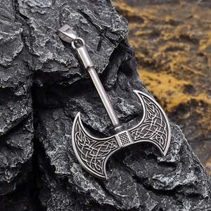 Close-up of silver Viking axe pendant with Celtic knots on a dark rocky background