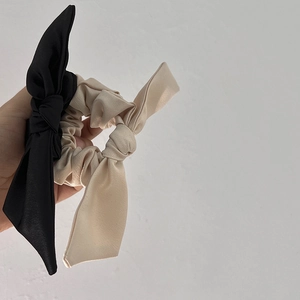 Détail de chouchous à nœud en satin fait main en couleurs crème et noir élégant