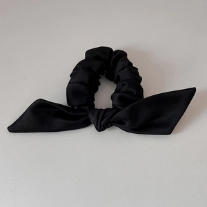 Vue détaillée d'un chouchou en satin noir avec un grand nœud et une texture soyeuse