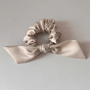 Détail d'un chouchou en satin champagne avec nœud et texture soyeuse élégante