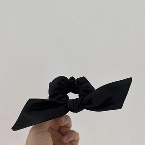Gros plan du chouchou noir à nœud en satin montrant la texture du tissu mat