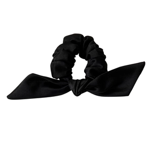 Chouchou élégant en soie noire avec nœud et plis doux sur un fond blanc minimaliste