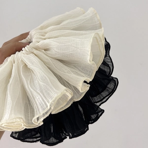 Close-up of pleated oversized hair scrunchies in cream and black chiffon fabric