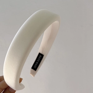 Close-up of thick cream sponge headband with HAND MADE label and woven texture