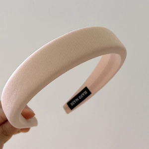 Detail of light pink padded sponge headband with handmade label and twill fabric texture