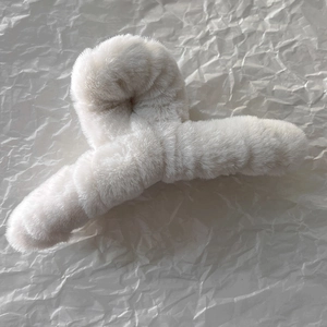 Gros plan sur la pince à cheveux en peluche ivoire montrant les détails en fausse fourrure