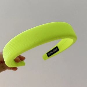 Detail of neon yellow sponge headband showing knitted texture and Hand Made label