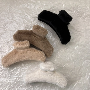 Detail showing four assorted faux fur claw clips in black, brown, apricot, and cream white