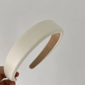 Detail of a thick cream PU leather headband showing side curvature and textured finish