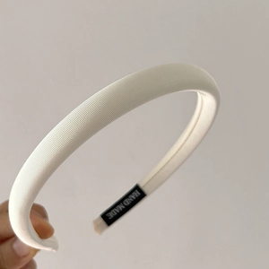 Detail of cream handmade headband with ribbed fabric texture and 'HAND MADE' label