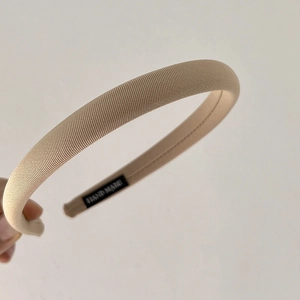 Detail of beige ribbed fabric headband with inner hand-made label and fine stitching
