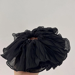 Detail of black oversized pleated scrunchie with soft chiffon texture and wavy edges
