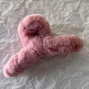 Gros plan d'une pince à cheveux en peluche rose avec texture douce sur papier blanc