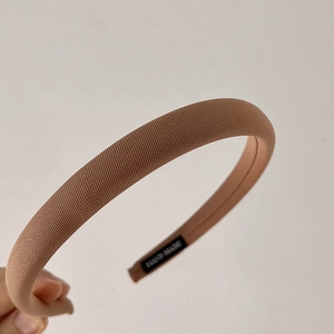 Detail of handmade padded headband featuring warm brown twill fabric and interior hand made label
