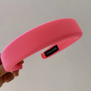 Detail of a bright pink padded sponge headband with HAND MADE label and ribbed texture