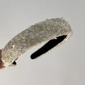 Gros plan détaillé du serre-tête en tweed crème avec fils dorés et paillettes