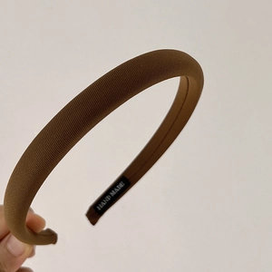 Detail of brown twill fabric headband with a stitched Hand Made label on the inside