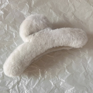 Détail d'une pince à cheveux en peluche crème avec texture douce en fausse fourrure