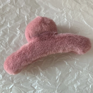 Gros plan détaillé d'une pince à cheveux en peluche rose sur fond de papier blanc
