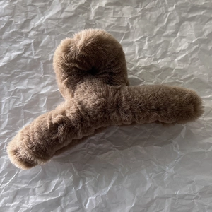 Détail d'une pince à cheveux en peluche marron foncé avec texture douce en fausse fourrure
