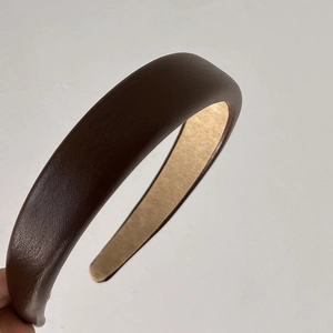 Detail of dark brown padded leather headband featuring premium lychee grain texture