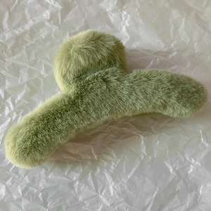 Détail d'une grande pince à cheveux peluche vert avocat avec texture en fausse fourrure