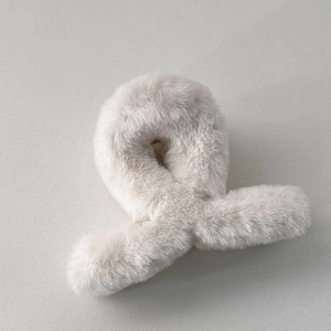 Gros plan d'une pince à cheveux en peluche beige montrant la texture douce et le ressort
