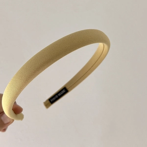 Macro shot of yellow fabric headband with a HAND MADE label stitched inside the band