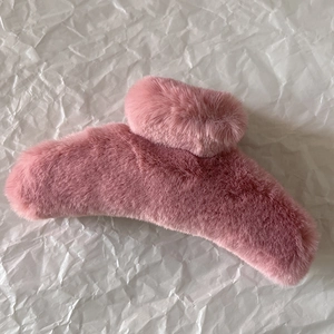 Close-up of soft pink plush hair claw clip on white textured paper background