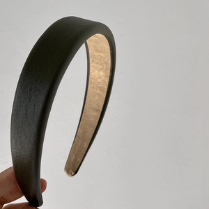 Detail view of dark green pebbled faux leather headband with anti-slip beige velvet lining