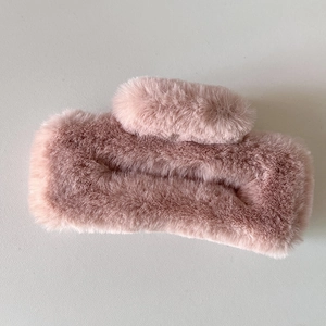 Détail d'une pince à cheveux en peluche rose clair avec une texture douce en fausse fourrure