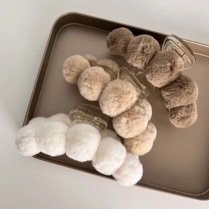 Three plush faux fur shark hair clips in white and brown shades on a gold tray