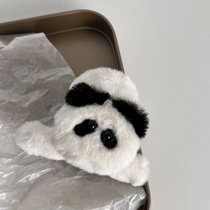 Dettaglio di una morbida clip per capelli in peluche a panda con fiocco nero su vassoio