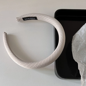 Gros plan d'un serre-tête beige en tissu côtelé avec une étiquette tissée Hand Made