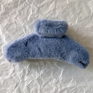 Detailed texture of blue faux fur hair claw clip on white textured paper background